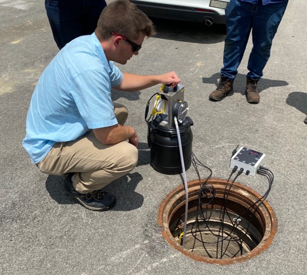 Photo of MSD employee sampling wastewater flow via a manhole